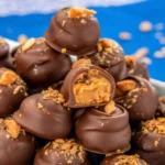 A close-up shot of homemade Butterfinger balls coated in chocolate, served on a parchment-lined tray.