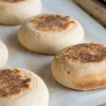 Sourdough English Muffins: Fluffy, Tangy Homemade Treat Every weekend, my kitchen fills with warm, tangy smells. These smells remind me of my grandmother's bakery. Making homemade sourdough English muffins is more than just baking. It's about making memories with each bite. These homemade English muffins are special. They're made with 75 grams of active sourdough starter. This gives them a taste that store-bought muffins can't match. They have perfect nooks and crannies, perfect for your favorite spreads. Whether you're an experienced baker or new to the kitchen, sourdough English muffins are a fun adventure. With a few simple ingredients and some patience, you'll make a breakfast treat that will be loved by your family for years. Key Takeaways Sourdough English muffins offer superior flavor and texture Homemade artisan bread allows complete ingredient control Active sourdough starter is key for authentic taste Total preparation time is about 14 hours and 45 minutes Recipe makes 10-12 delicious English muffins The Art of Making Sourdough English Muffins Making bakery-style muffins at home needs passion, precision, and a good grasp of fermented dough techniques. Sourdough English muffins are a fun culinary journey. They mix old baking ways with science. Starting with sourdough English muffins means understanding the sourdough starter. This living culture turns simple ingredients into a tasty, complex masterpiece. Understanding Active Sourdough Starter An active sourdough starter is key for those tangy flavors and light texture. Your starter should be: Bubbly and vibrant Doubling in volume within 4-8 hours Showing consistent fermentation patterns Essential Equipment and Tools Getting ready for sourdough needs specific kitchen tools: Large mixing bowl Digital kitchen scale Griddle or cast-iron skillet Parchment paper Measuring cups and spoons Key Ingredients for Success Choosing the right ingredients is key for great fermented dough. Use high-protein bread flour, filtered water, and a strong sourdough starter. This mix makes bakery-style muffins with deep flavor. A typical recipe needs: Flour: 2 1/2 cups high-protein bread flour Water: 1 cup filtered water Sourdough starter: 1/2 cup active starter Salt: 1 teaspoon Honey: 1 tablespoon (optional) Pro tip: Always use a fresh, active sourdough starter for the best rise and flavor development. Perfect Timing: Overnight Fermentation Process The secret to making amazing artisan bread is the overnight fermentation. Time is the key ingredient when working with fermented dough. It turns simple ingredients into a true culinary delight. Here are the key steps for a successful overnight fermentation: Cover the dough with a clean kitchen towel Place in a warm location (around 70°F) Allow 8-10 hours for complete bulk fermentation Watch for the dough to double in size Ancient grains are important in the fermentation process. The long fermentation time breaks down proteins and makes nutrients easier to digest. This method not only boosts flavor but also improves digestibility. Fermentation Parameter Recommended Value Room Temperature 70°F (21°C) Bulk Rise Time 8-10 hours Dough Volume Increase Double original size Maximum Fermentation Temp 28°C Professional bakers know that patience is essential. The slow fermentation creates incredible depth of flavor that can't be rushed. By letting the dough rest overnight, you make English muffins with unmatched taste and texture. "Fermentation is not just cooking; it's an art form that transforms simple ingredients into something extraordinary." - Artisan Baker To get the best results, keep an eye on your dough's progress. Adjust the timing based on your kitchen's conditions. The magic of sourdough comes from its living, breathing nature. Mastering the Basic Dough Preparation Making homemade English muffins needs precision and knowing how to work with fermented dough. The process starts with picking the right ingredients and mixing them just right. This turns simple stuff into a tasty treat. Mixing Techniques for Perfect Texture When making sourdough English muffins, picking the right flour is key. Bread flour has 12%-14% protein, making it better than all-purpose flour's 9%-11%. Use a Danish Dough Whisk for mixing to make sure everything is evenly spread out. Start by combining active starter with warm milk Gradually add flour and salt Stir until a rough dough forms Temperature and Hydration Control Getting the hydration right is important for making great homemade English muffins. Aim for 60% to 70% hydration. This helps the dough ferment well. Fermentation Stage Temperature Range Duration Bulk Fermentation 68-78°F (20-26°C) 12-18 hours Final Proofing 70-75°F (21-24°C) 1¾ - 2½ hours Signs of Proper Fermentation Knowing when the dough is fermented right is important for great sourdough English muffins. Look for these signs: Significant volume increase Visible air bubbles Soft, elastic texture Slightly tangy aroma "Patience is the secret ingredient in sourdough baking" - Artisan Baker's Wisdom Shaping and Cutting Techniques Making perfect homemade English muffins needs careful shaping and cutting. These muffins must have a round shape and even texture. This is key to their bakery-style quality. Here are the important steps for shaping your English muffin dough: Dust your work surface with semolina flour to prevent sticking Roll the fermented dough to a precise 1/2 inch thickness Use a 3.5-inch round cookie cutter for uniform muffin sizes Gently press cutter straight down without twisting Professional bakers use special cutting techniques for perfect homemade English muffins: Cutting Tool Advantages Recommended Use Round Cookie Cutter Uniform shape Best for professional results Drinking Glass Home kitchen alternative Quick and easy method English Muffin Ring Perfect height and width Ideal for consistent sizing After cutting, let the muffin rounds rest for 5 minutes before cooking. This short break relaxes the gluten. It makes the muffins tender and of bakery-style quality. Creating Those Signature Nooks and Crannies Making the perfect English muffin is all about creating those beloved nooks and crannies. This is what makes the bread so irresistible. The griddle cooking method is essential for achieving the iconic texture that home bakers love. To develop those characteristic air pockets, follow these essential steps: Preheat your griddle to a consistent 325°F (163°C) Use a low and slow cooking approach Cook for approximately 5-6 minutes per side Watch for golden-brown coloration Traditional Griddle Cooking Technique The magic of nooks and crannies happens during careful griddle cooking. Sprinkle a light dusting of cornmeal on the surface to prevent sticking and create additional texture. Cook the muffins gently, allowing steam to create internal air pockets that define the classic English muffin structure. Temperature Control for Even Browning Precise temperature management is key for perfect English muffins. Aim to maintain a steady 325°F (163°C) throughout cooking. Use an instant-read thermometer to check the internal temperature, which should reach 190°F (88°C) for fully cooked muffins. Pro tip: Flip the muffins only once to ensure even cooking and preserve those delightful nooks and crannies that make this breakfast bread a culinary delight. Storage and Freezing Methods Keeping your sourdough English muffins fresh is key. Homemade English muffins can stay tasty for days or weeks with the right storage. This ensures you can enjoy your breakfast bread for a long time. For a short-term fix, store your muffins at room temperature. Here's how to keep them fresh: Store in an airtight container Keep at room temperature Consume within 5 days for optimal taste Freezing is great for longer storage. Freezing can keep your homemade English muffins fresh for up to 3 months. Here's how to freeze your sourdough English muffins: Cool muffins completely after cooking Place in freezer-safe resealable bags Remove excess air to prevent freezer burn Label with the date of freezing Thawing frozen breakfast bread is easy. Just take out what you need and let it sit at room temperature for 10 minutes. For a quick warm-up, microwave for about 10 seconds. Pro tip: Don't refreeze thawed English muffins. Always separate them with parchment paper before freezing to prevent sticking. Serving Suggestions and Toppings Your freshly baked sourdough English muffins open up a world of culinary creativity. They can turn simple meals into gourmet experiences. With 20 unique English muffin recipes, you'll find endless ways to make them delicious. Sweet lovers will enjoy classic combos like homemade butter with honey or cinnamon sugar. Savory fans will love the 15 out of 20 recipes that offer hearty options. Try a breakfast sandwich with scrambled eggs, cheese, and bacon, or go for Huevos Rancheros or avocado toast. Make your English muffin game better by trying gourmet toppings. Add vegetables, cheese, and unique sauces to your recipes. From pizza-inspired to elegant Eggs Benedict, these muffins can be breakfast, lunch, or dinner. They're not just a meal; they're a canvas for your creativity. Pro tip: Always toast your English muffin to get the perfect texture. It's great for absorbing spreads and toppings. Whether you like sweet or savory, these muffins will be a favorite in your kitchen. FAQ What makes sourdough English muffins different from regular English muffins? Sourdough English muffins have a tangy flavor and are easier to digest. This is because of the natural fermentation process. The sourdough starter adds deeper flavors and breaks down gluten, making them more digestible than commercial muffins. How long does it take to make sourdough English muffins from start to finish? Making sourdough English muffins takes 12-24 hours. This includes the overnight fermentation. You'll spend about 1-2 hours actively preparing, with the rest of the time letting the dough ferment slowly. Do I need a special starter to make sourdough English muffins? You need an active sourdough starter that's bubbly and vigorous. If you don't have one, you can make your own or get one from a local bakery or friend. Can I freeze homemade sourdough English muffins? Yes, you can freeze them well. Cool them completely, then store in a freezer-safe bag for up to 3 months. Thaw at room temperature or toast from frozen for the best taste. What are the best ways to cook sourdough English muffins? Cook them on a cast-iron griddle or heavy skillet over medium-low heat. This method creates the signature nooks and crannies and ensures an evenly cooked, golden-brown exterior. Are sourdough English muffins healthier than store-bought versions? Homemade sourdough English muffins are healthier. You control the ingredients, can use whole grains, and benefit from the fermentation process. This increases nutrient availability and digestibility. How can I ensure I get those classic nooks and crannies? To get nooks and crannies, ensure proper dough hydration and gentle handling. Cook on low, consistent heat. Use a fork to split the muffins instead of cutting to maximize those texture pockets. What are some creative ways to use sourdough English muffins? Use them as mini pizza bases, for avocado toast, or as a base for eggs Benedict. They're also great as a side for soups and salads. They're versatile for both sweet and savory dishes.