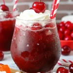 Cherry Rum and Coke Slushie in a glass with a maraschino cherry garnish.