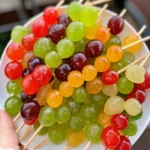 Close-up of Jolly Rancher candy-coated grapes, a sweet fruit treat covered in colorful candy.