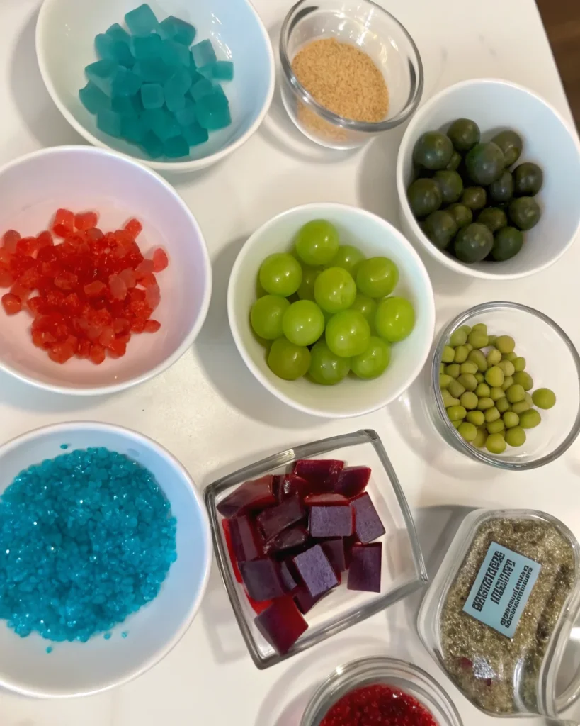 Skewered Jolly Rancher candy grapes coated with colorful sugar crystals and rock candy, arranged on a white surface.