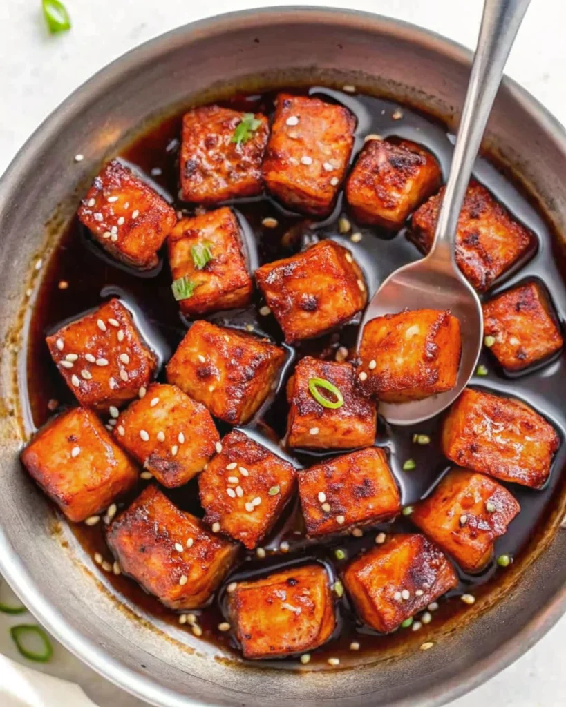 Crispy Honey Garlic Salmon Bites served on a bed of fluffy white rice, garnished with sesame seeds and green onions.