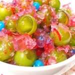 Colorful candy grapes coated in crushed Jolly Ranchers, displayed on a white plate