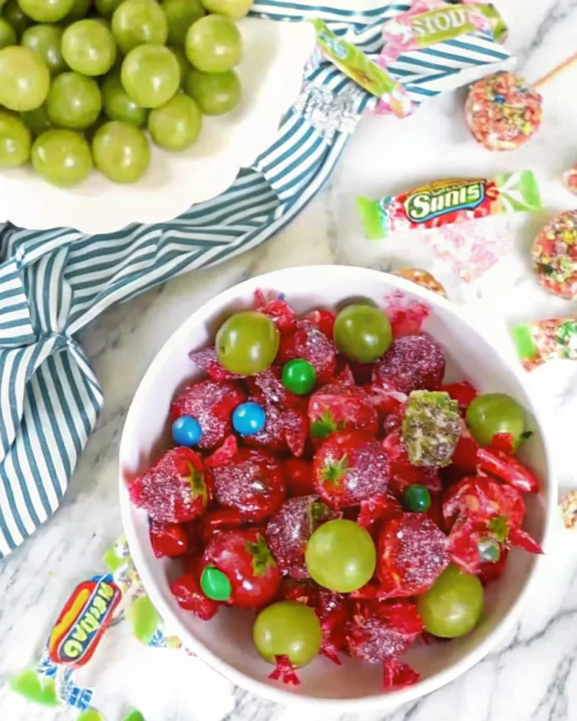 Colorful candy grapes coated in crushed Jolly Ranchers, displayed on a white plate