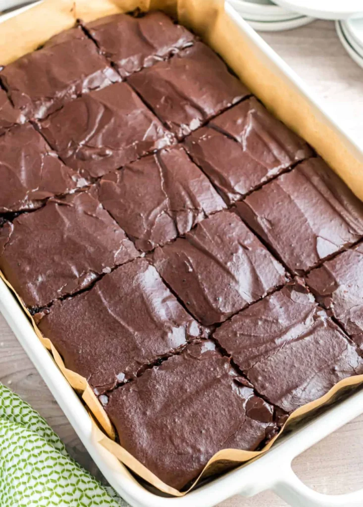 Fudgy chocolate zucchini brownie topped with rich chocolate frosting on a white plate.