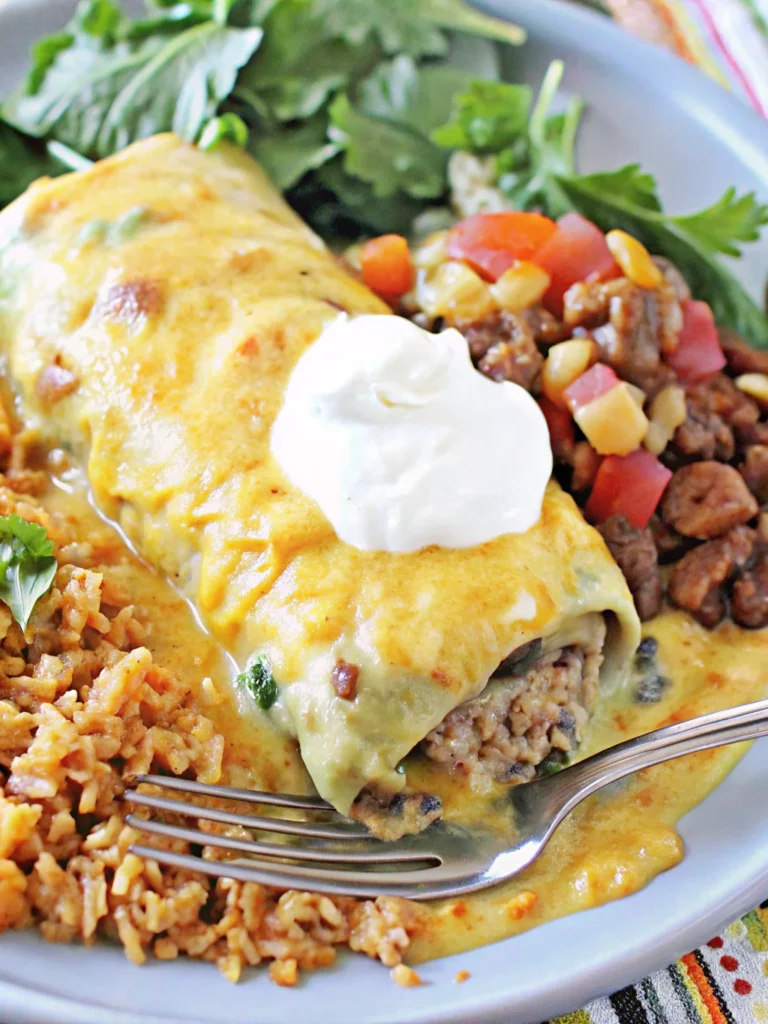 Smothered green chili burrito topped with melted cheese and sour cream, served with Mexican rice, beans, and fresh greens.