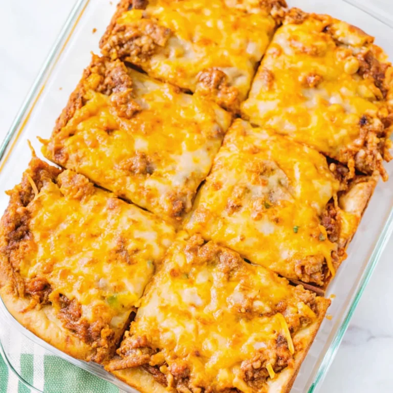Golden, cheesy burrito bake cut into six squares inside a clear glass baking dish. The dish features a crispy crescent dough crust, savory beef and bean filling, and a bubbly melted cheese topping.