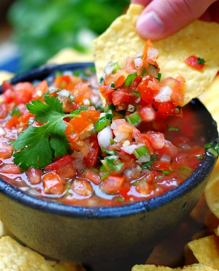 Fresh salsa with cilantro lime recipe—bowls of chunky salsa made with fresh tomatoes, onions, jalapenos, and cilantro, garnished with a tortilla chip and lime.