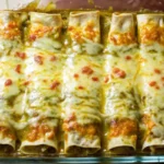 Hatch green chile enchiladas baked in glass dish with melted cheese and red chile sauce, featuring roasted New Mexico chiles and corn tortillas