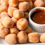 Air fryer churro bites coated in cinnamon sugar served on a plate with chocolate dipping sauce – a healthy homemade fall snack.