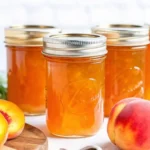 Homemade peach jam recipe in glass jars with fresh peaches, showcasing easy canning peach jam process for summer fruit preserves.