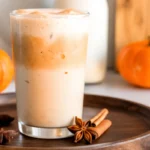 Iced pumpkin cream chai tea with pumpkin foam and fall spices in a glass.