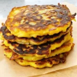 Stack of golden crispy Parmesan yellow squash fritters on parchment paper showing perfect browning and texture
