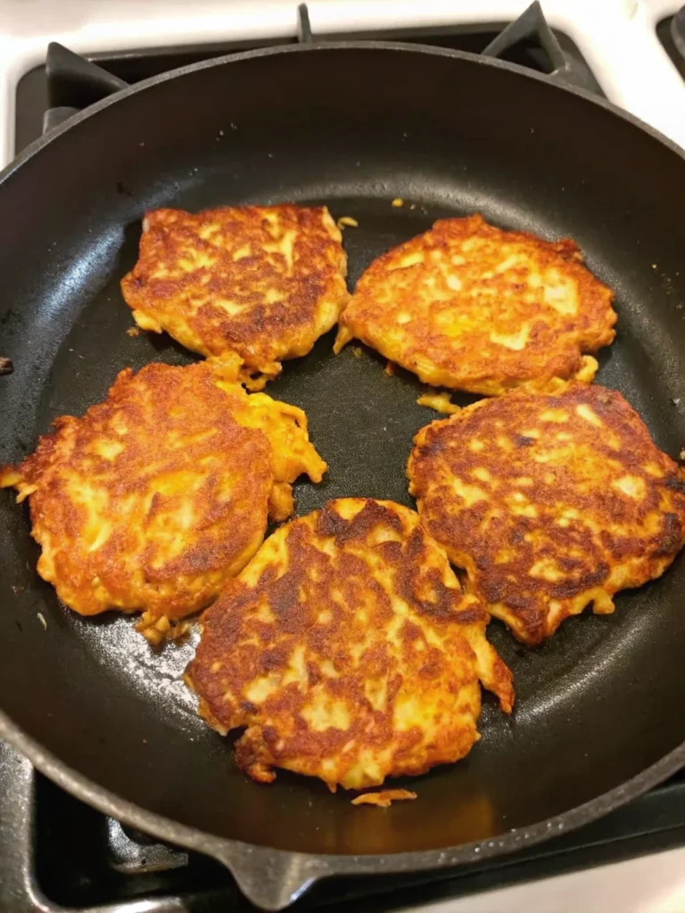 Stack of golden crispy Parmesan yellow squash fritters on parchment paper showing perfect browning and texture