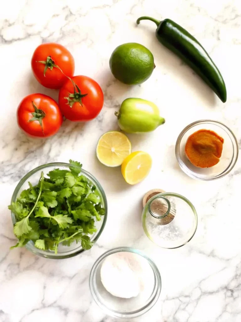 Fresh salsa made with tomatoes, cilantro, jalapenos, and lime juice in a white bowl, garnished with fresh herbs.