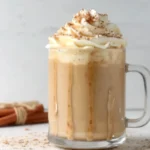 Homemade pumpkin spice latte recipe with whipped cream topping and cinnamon sticks garnish in clear glass mug