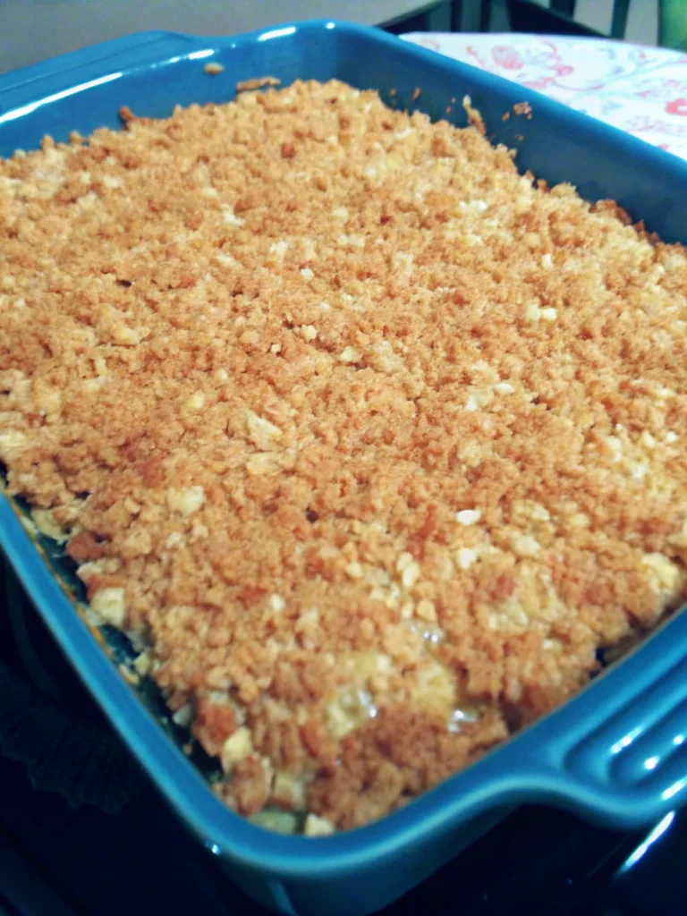 Homemade squash casserole with golden crushed Ritz crackers on top, showing creamy yellow squash filling underneath