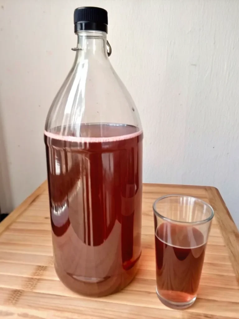 Homemade fire cider recipe in glass jar showing colorful layers of citrus, onions, ginger, turmeric, and apple cider vinegar for immune support