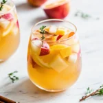 A glass of apple cider cocktail with Prosecco, garnished with fresh fruits, thyme, and cinnamon sticks—refreshing autumn sangria on a marble background.