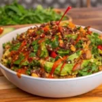Delicious crispy rice salad with avocado, cilantro, and spicy peanut-chili dressing, topped with fresh vegetables and crushed peanuts.