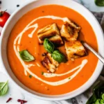 Bowl of creamy homemade roasted tomato soup with fresh basil garnish made from fresh vine tomatoes