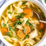 Homemade chicken noodle soup with tender shredded chicken, egg noodles, carrots, and celery in rich golden broth served in white bowl
