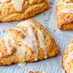 Golden pumpkin scones arranged on parchment paper with visible flaky layers and aromatic spices, showcasing the perfect autumn breakfast treat from this easy pumpkin scones recipe