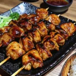 Authentic Japanese chicken yakitori skewers with glossy teriyaki glaze being grilled over charcoal, showing perfect caramelization and traditional bamboo skewers, japanese recipe ideas for home cooking