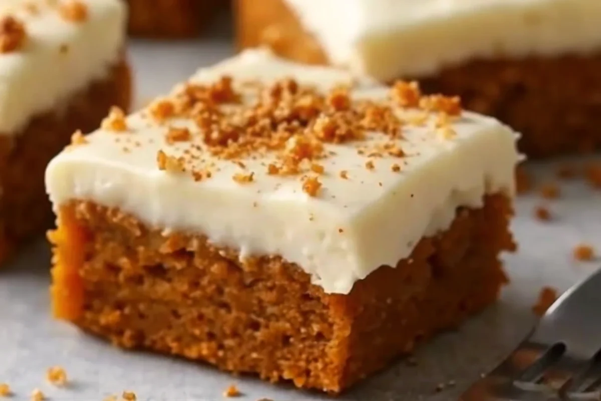 Perfectly frosted pumpkin bars with cream cheese frosting cut into squares, showing moist orange cake texture topped with white frosting