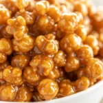 Golden Amish caramel corn with almonds spread on parchment paper, showing glossy caramel coating and perfect texture