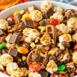 Fall snack mix in rustic wooden bowl featuring caramel corn, pretzels, colorful candies and candy corn for autumn parties