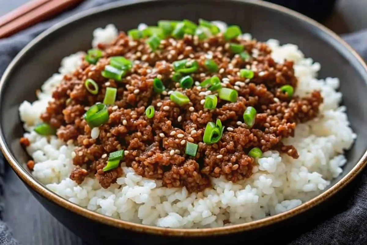 Korean ground beef bowl with seasoned rice, garnished with green onions and sesame seeds in a white ceramic bowl