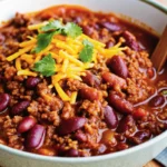Hearty Pioneer Woman chili soup in a large Dutch oven with colorful toppings including shredded cheese, sour cream, and green onions