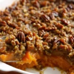 Golden-brown sweet potato crunch casserole with caramelized pecan topping and maple syrup glaze in white baking dish