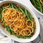 Golden brown thanksgiving green beans casserole with crispy fried onions and melted cheese in white baking dish