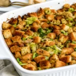 Golden brown homemade stuffing recipe in baking dish with fresh herbs and butter, perfect for Thanksgiving dinner